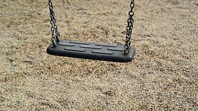 Empty swing seat swaying at playground in the park.