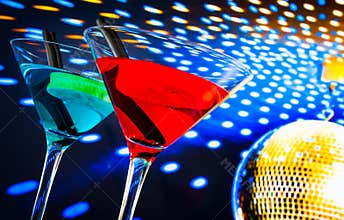 Blue and red cocktail with golden sparkling disco ball background with space for text