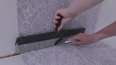 Trimming excess paper. Trimming wallpaper in the corners of a room after wallpapering.