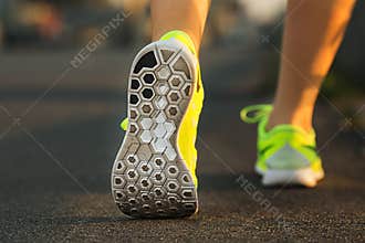 Runner woman feet running on road closeup on shoe. Female fitness model sunrise jog workout. Sports lifestyle concept.