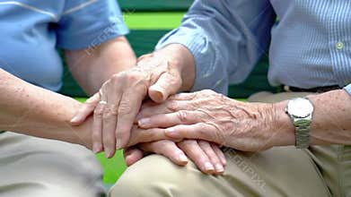 Close-up on the wrinkled hands of an elderly man and woman, symbolizing a lifetime of love