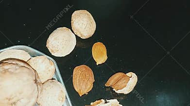 Metallic tin of almonds with a single walnut and cracked dry fruits display