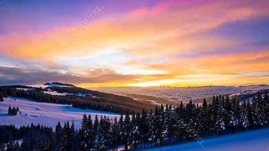 Beautiful Sunset Over Snowy Mountains and Evergreen Forest in Winter