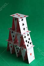 House of playing cards on green background