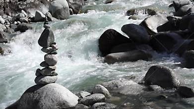 Balanced stone cairn on Ala-Archa riverbank amid rushing mountain stream. Boulders, trekking, alpine climbing, hiking, backpacking