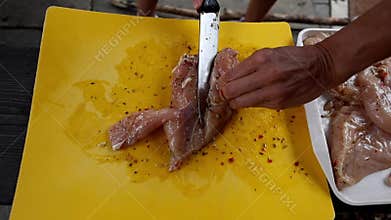 Filleting marinated chicken breasts for grilling