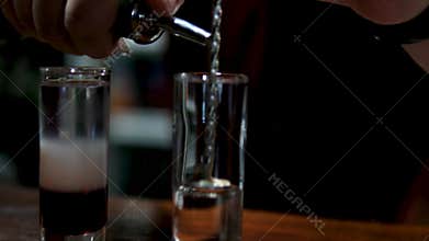 Bartender pouring vodka into shot glasses at the bar.