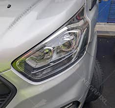 Close up view of a modern car headlight during daylight on a city street