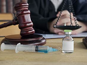 courtroom with a gavel and syringe next to a vial representing legal issues and health and medicine. Coronavirus vaccines. Lethal