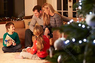 Family Exchanging Gifts By Christmas Tree