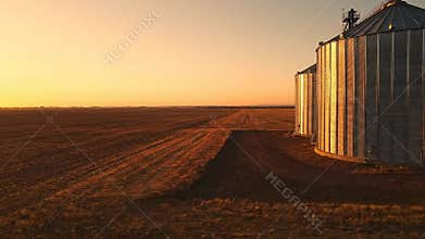 Wheat Field and Silo During Sunset in Rural Landscape Warm Light Reflection in Agricultural Field for Food Production, Farming