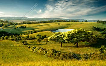 Beautiful hilly landscape with lake and blue cloudy sky