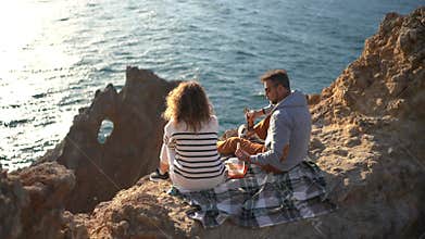 Adventurous Couple Picnic High Cliff Overlooking Sparkling Ocean View.