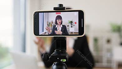 Professional woman recording a business vlog in a modern office setting
