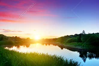 Lake in forest at sunset. Romantic sky