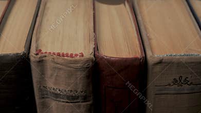 Close up of old hardcover books arranged vertically with visible page edges