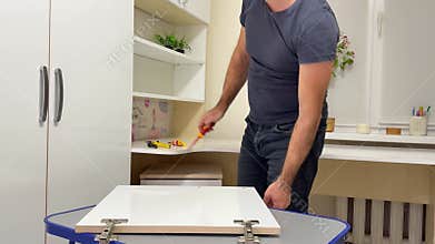 Man assemble furniture craftsman assembles furniture fittings. Twisting the confirmat close-up. Professional furniture