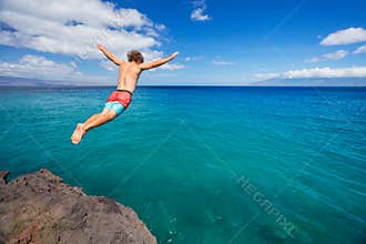 Man jumping off cliff into the ocean