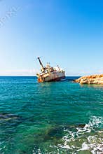 The Edro III, Pegeia, Cyprus - rusty shipwreck drifts on turquoise water off rocky coast under clear blue sky