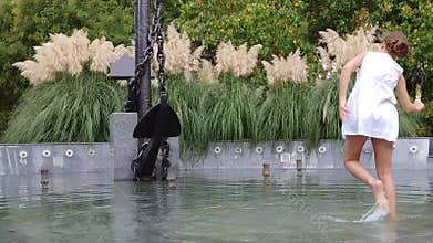 Girl is in the water, wearing a white dress in anchor fountain