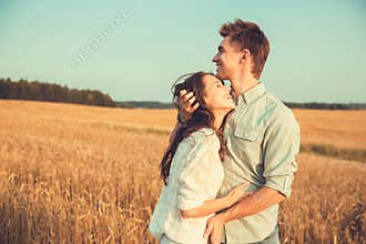 Young couple in love outdoor. Couple hugging. Young beautiful couple in love staying and kissing on the field on sunset.