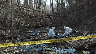 Forensic specialist working in the forest. Police criminalists collecting evidence and making criminal investigation