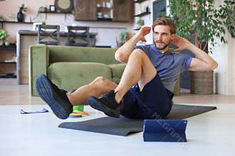 Handsome man doing abs exercises at home during quarantine. Concept of healthy life