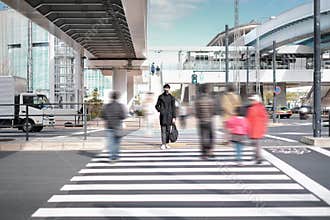 Young man wear black face mask and waiting to crossing road under the concrete bridge near electric train station in Tokyo, Japan