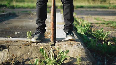 Feet and a baseball bat stands between your feet on the asphalt. Troublemaker