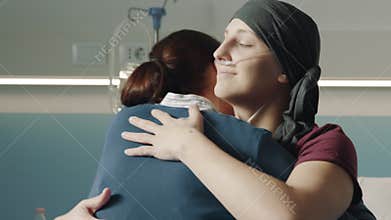 Caring woman hugging her friend with cancer at the hospital