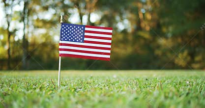 Small American, US or USA, flag waving in the wind outside in the grass