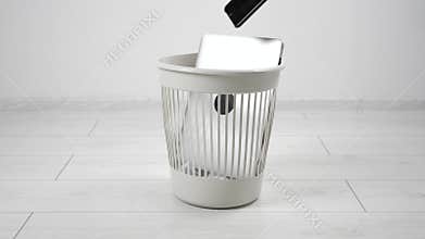 Close-up throwing laptop computer and smartphone to the trash bin. The concept of getting rid of gadgets and electronics