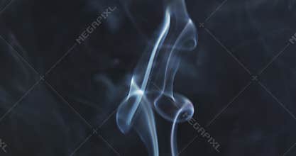 Blue smoke rising over black background in slow motion