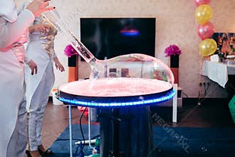 Soap bubble table with a big soap ball. Animators inflating a soap ball. Show on the birthday of the child