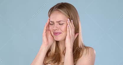 Portrait of an young woman with strong headache or migraine. Pain emotions on her face.