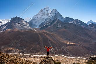 A trekker standing on rock and looking to Ama Dablam mountain peak in Dingboche village, Everest base camp trekking route, Nepal