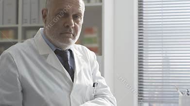 Confident doctor checking medical records and smiling at camera