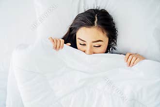Top view of sleeping asian woman cover face with blanket flat lay. Close-up of young women, sleeping under white blanket