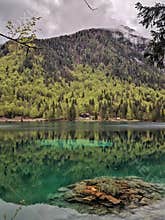 Rocky island in aquamarine mirroring lake among mountains and woods