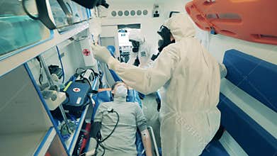 A patient in the ambulance with doctors in hazmat suits. Coronavirus, COVID-19 concept.