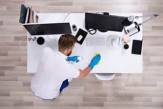 Janitor cleaning white desk in office