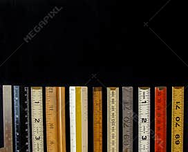 A straight line of rulers and scales in metric and inches suggest measurement, metrics, precision, accuracy