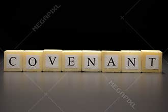 The word COVENANT written on wooden cubes isolated on a black background