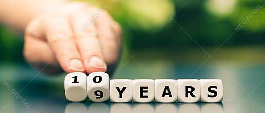 Hand turns dice and changes the expression `9 years` to `10 years`.