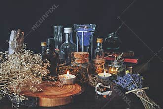 Wiccan witch apothecary - various ingredients, potions and dried herb bottles and jars for magick, placed on an altar.