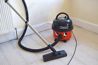 Old vacuum cleaner Henry with funny design in home interior.
