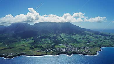 Aerial footage of Mount Liamiuga on a green island with tropical forests and small town Saint Kitts and Nevis
