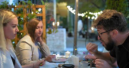 Happy family eats sushi sitting at table with different dishes