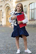 Learning and fun for everyone. Happy kid hold books and toy. Back to school supplies. School uniform. Formal fashion