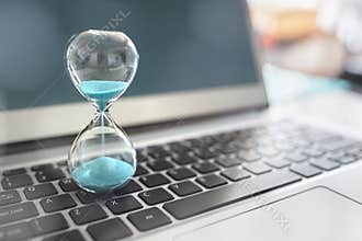 Hourglass on laptop computer concept for time management